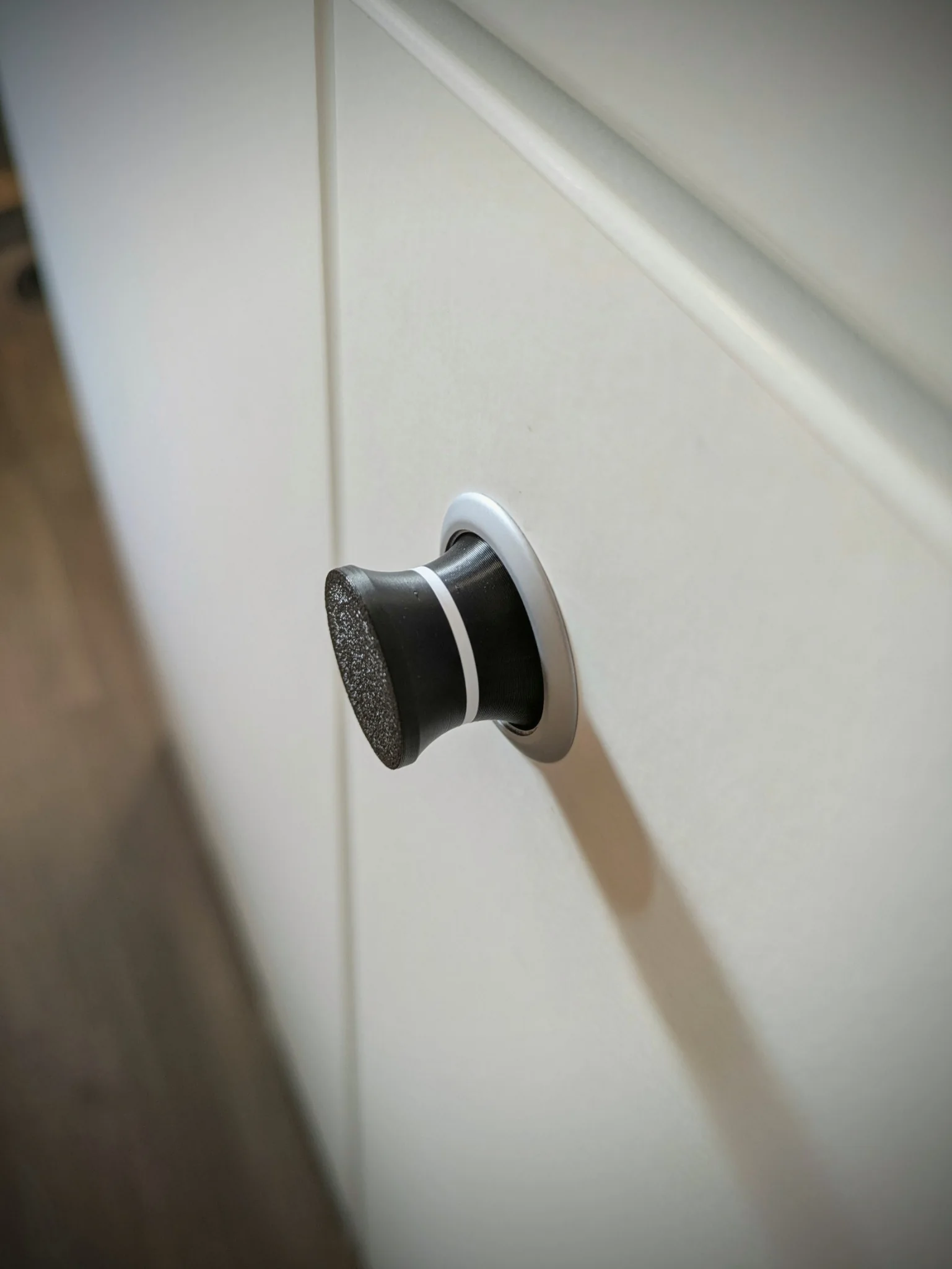 Bouton noir renforcé avec bague blanche de repérage installé sur un placard de fourgon