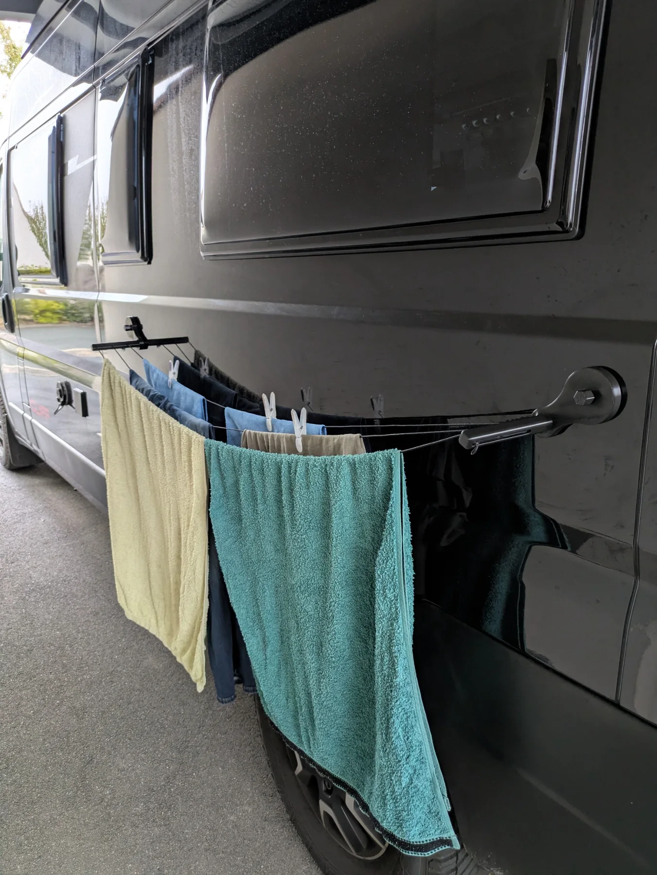 Étendoir magnétique Fourgon Malin installé le long d’un fourgon avec serviettes et vêtements