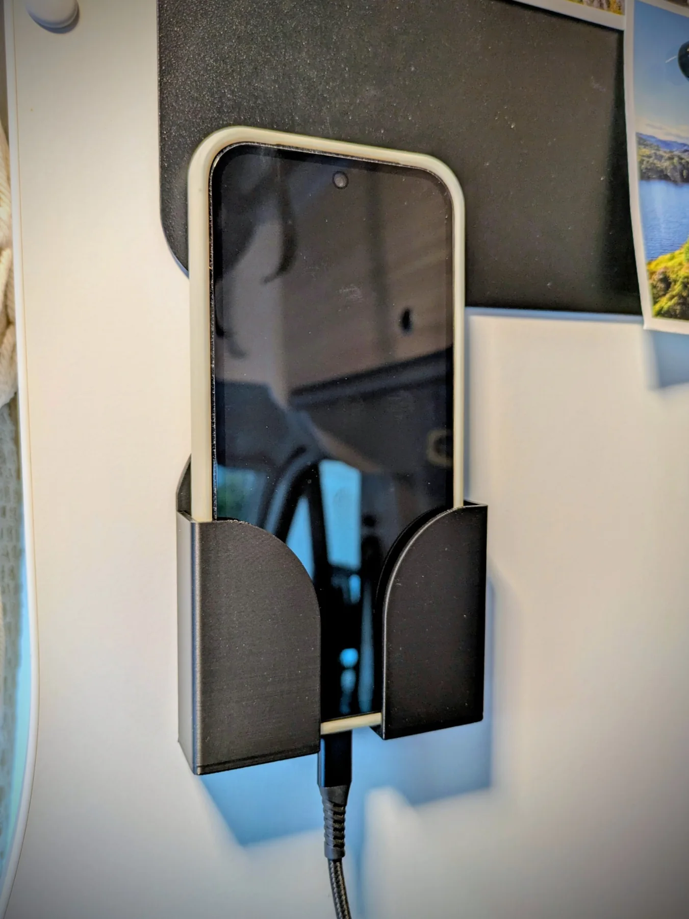 Smartphone placé verticalement dans le support mural noir pendant la recharge